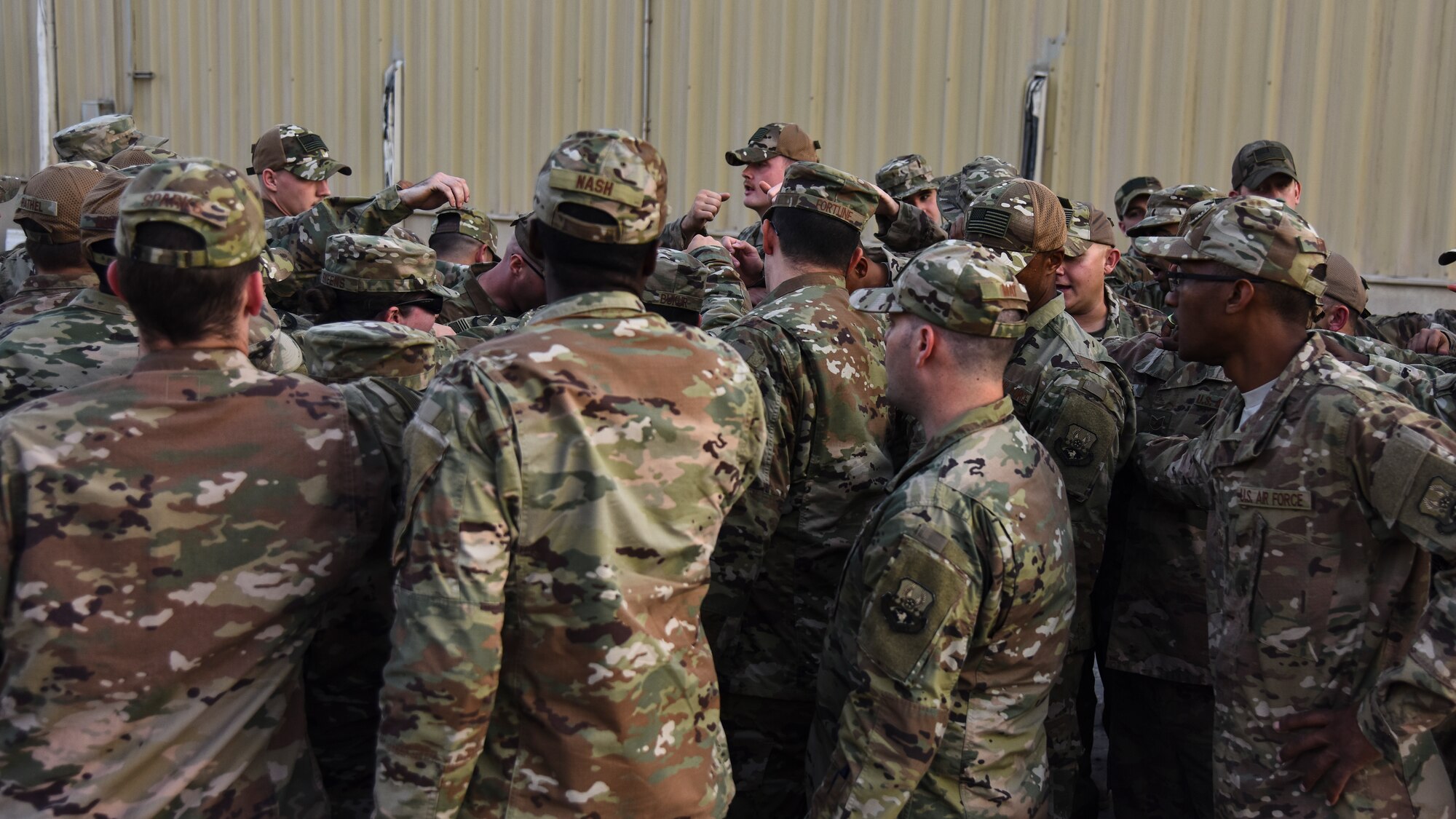 U.S. Airmen assigned to the 380th Expeditionary Logistics Readiness Squadron huddle together during a tribute to fallen ground transportation Airmen at Al Dhafra Air Base, United Arab Emirates, Nov. 8, 2018. The 380th ELRS takes the time every Thursday to make sure that the lives and legacies of the fallen Airmen continue to prevail. (U.S. Air Force photo by Senior Airman Mya M. Crosby)
