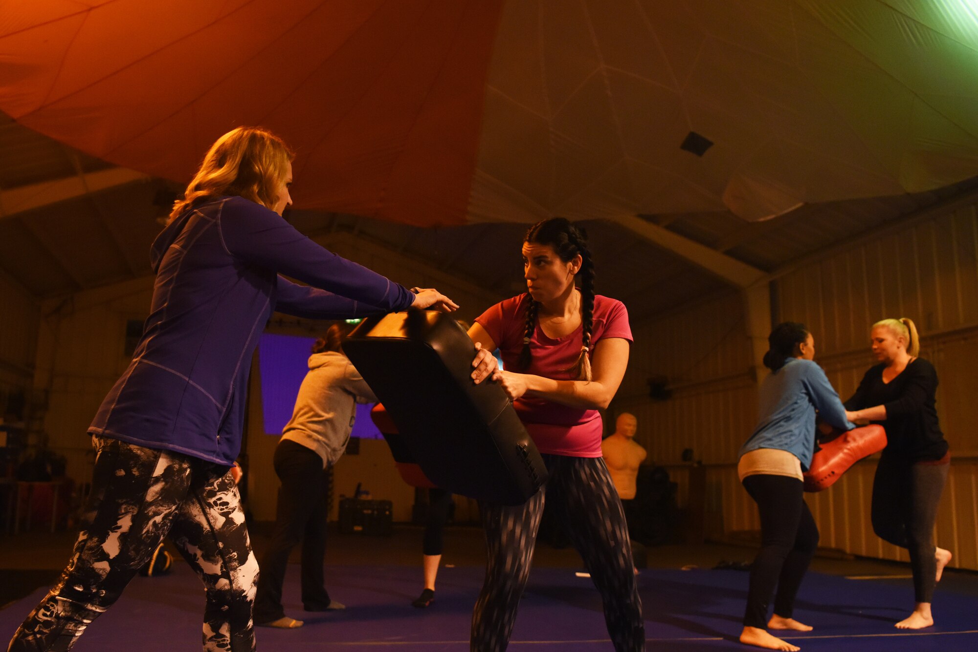 Women practice knee strikes during a self-defense class hosted by Survival, Evasion, Resistance and Escape specialists, assigned to the 48th Operation Support Squadron, on Royal Air Force Mildenhall, England, Nov. 14, 2018. The SERE specialists gave instructions concerning the most vital places to strike an attacker and the most effective way to inflict damage for escape. (U.S. Air Force photo by Airman 1st Class Shanice Williams-Jones)