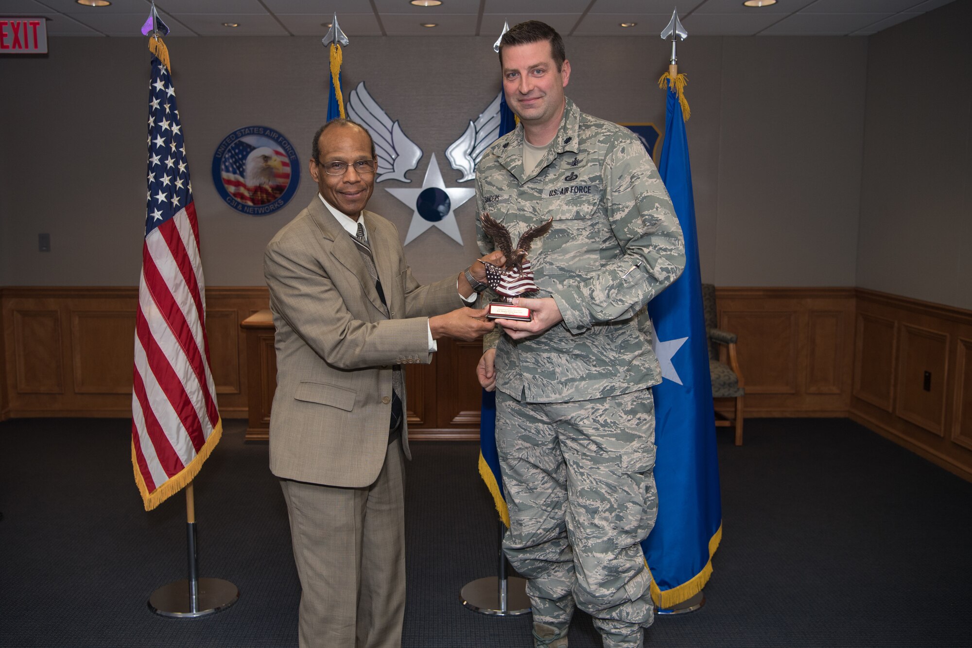 Program Executive Office Digital Program Management Senior Functional David Temple, left, presents the award for Outstanding Program Office to Lt. Col. Jeremiah Sanders, Air Operations Center weapons system senior materiel leader for PEO Digital, at the Air Force Life Cycle Management Center Program and Test Management annual awards, broadcast to Hanscom Air Force Base, Mass., Nov. 14. Sanders accepted two awards on behalf of the Project Kessel Run team and his program office, each of which were recognized for designing applications used by combatant commanders to orchestrate air operations in the Middle East and worldwide. (U.S. Air Force photo by Jerry Saslav)
