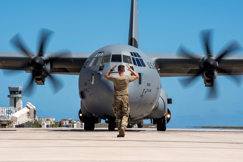 An airman marshals in a C-130J Super Hercules