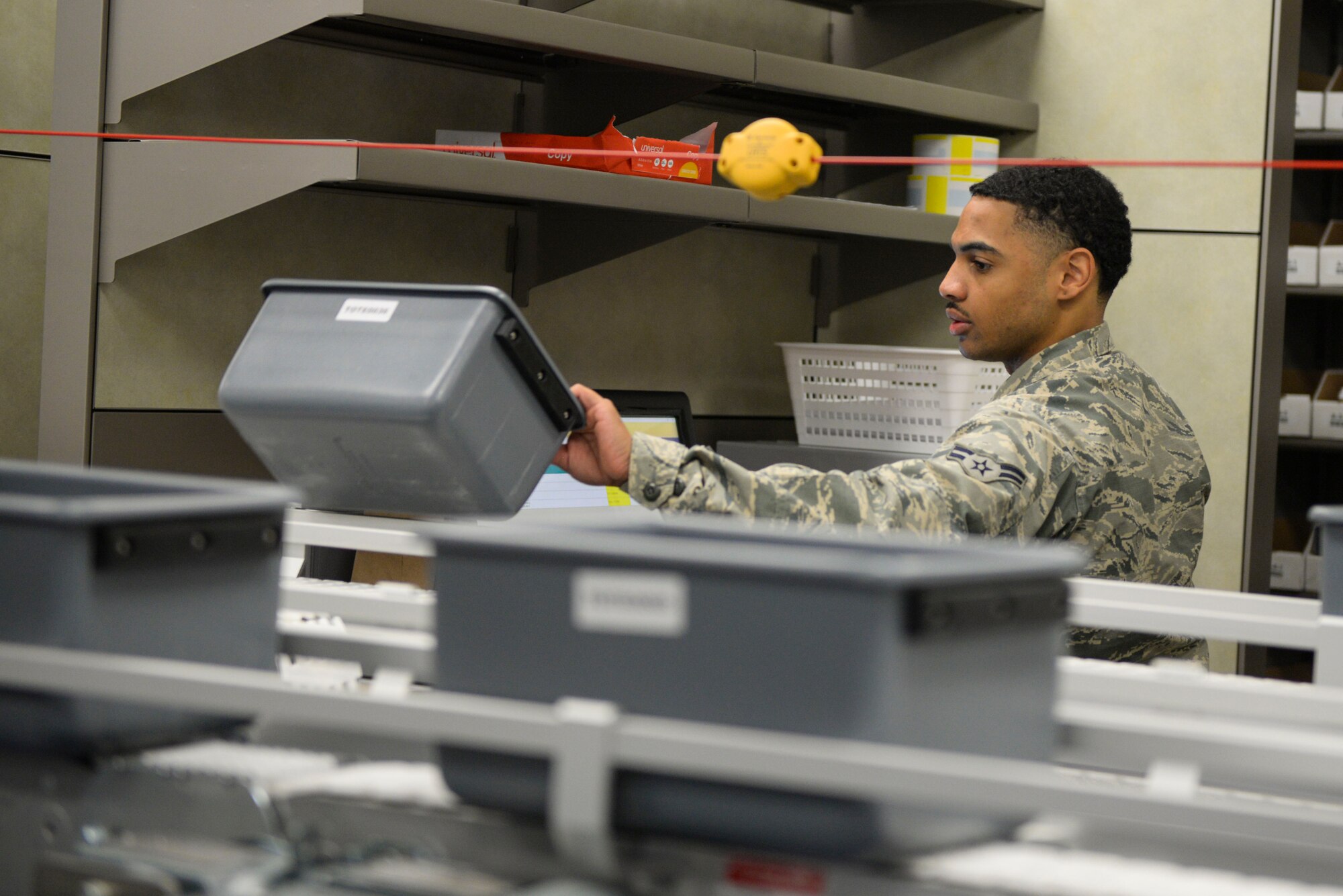Airman 1st Class John Richardson, 88th Medical Group pharmacy technician, grabs a transport bucket off the conveyor belt for packaging, inside the new Kittyhawk Satellite Pharmacy, Nov. 13, 2018, at Wright-Patterson Air Force Base, Ohio.