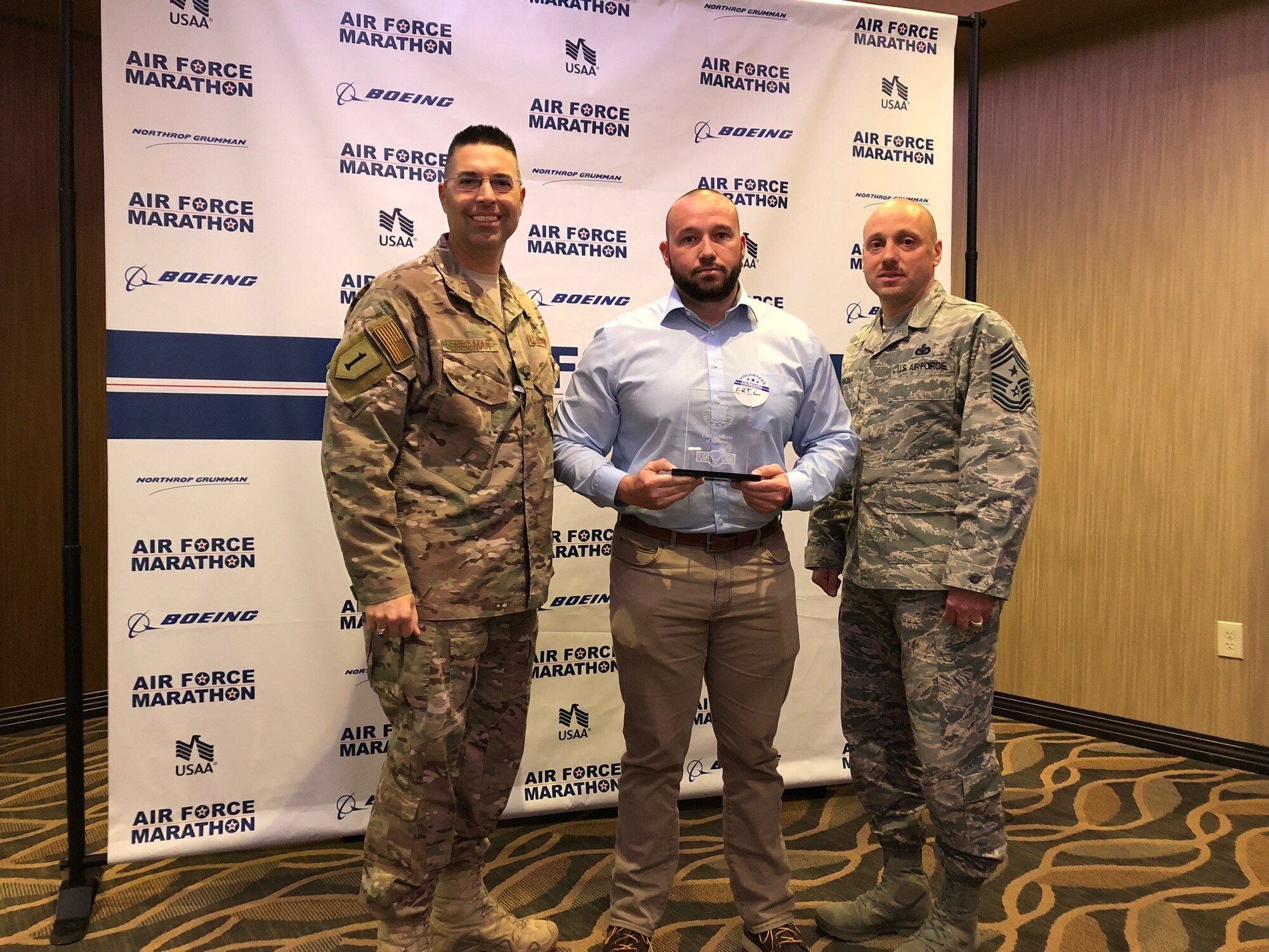 Col. Thomas Sherman, 88th Air Base Wing and Installation commander (left) and Chief Master Sgt. Stephen Arbona, 88 ABW command chief present the Air Force Marathon Expo Volunteer of the Year award to Eric Hoehne at a volunteer reception held Oct. 17 at Soin Medical Center.  (Courtesy photo)