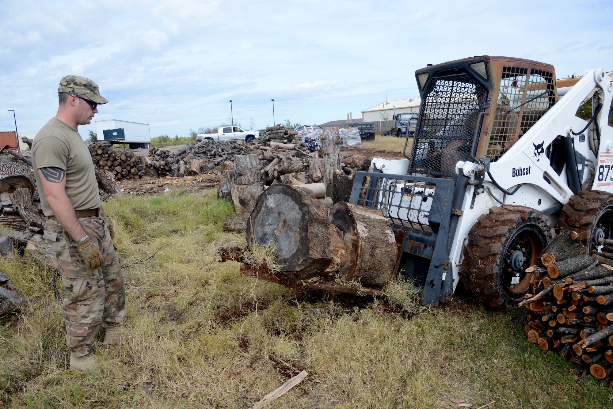 Staff Sgt. Eric Gibson drives the forklift to relocate large stumps to their designated pile, while Staff Sgt. Josh Dowding makes sure everything stays in place. Members of the 76th Expeditionary Maintenance Squadron are volunteering with Natural Resources to help move, organize and split wood to sell for firewood, furniture or other projects.