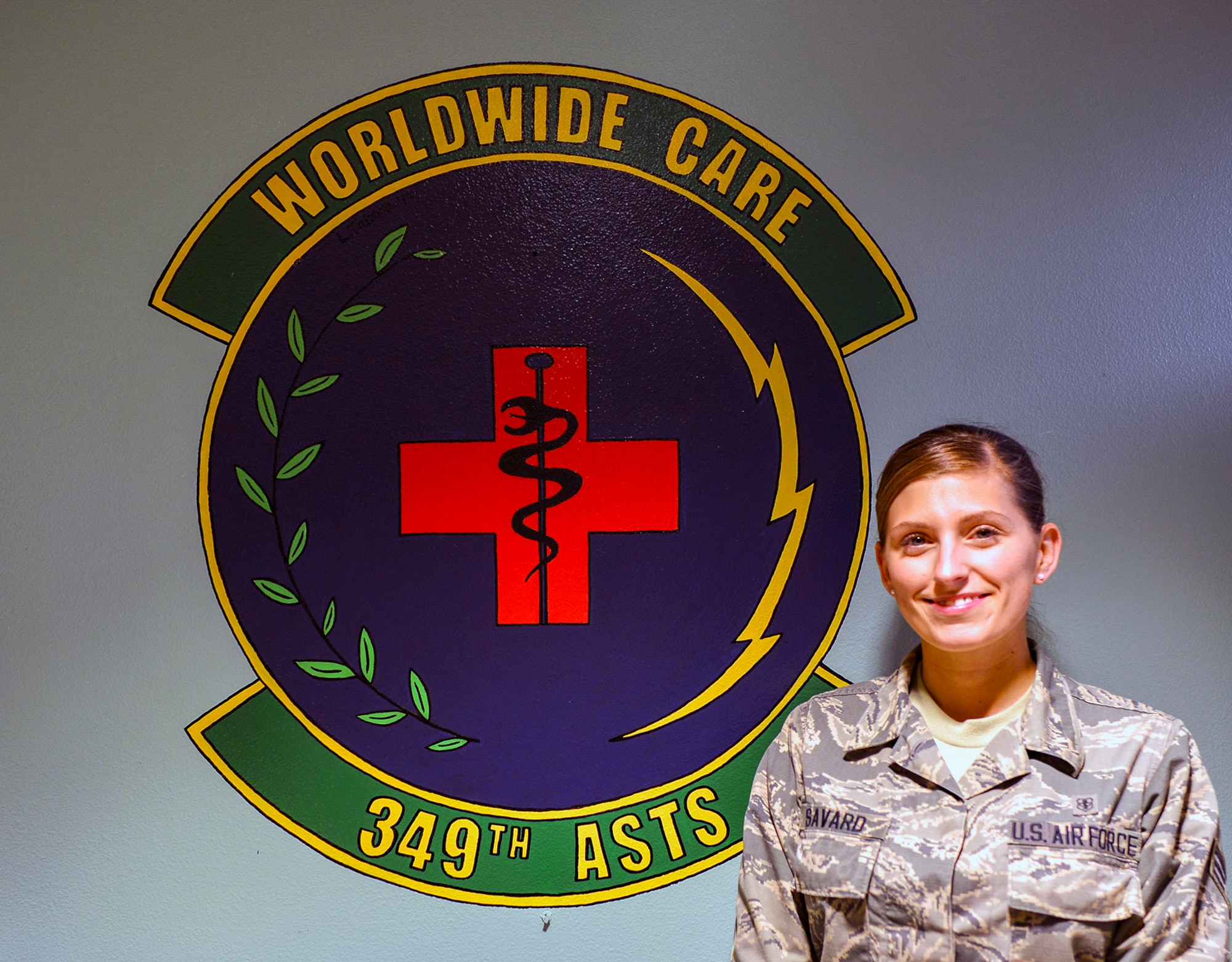 Senior Airman Nichole Savard, 349th Aeromedical Staging Squadron unit deployment manager, poses for a photo in front of her unit shield Nov. 4, 2018 at Travis Air Force Base, California.