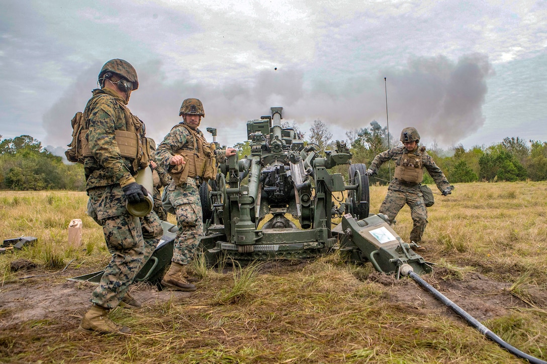 Marines work as a team to load a howitzer.