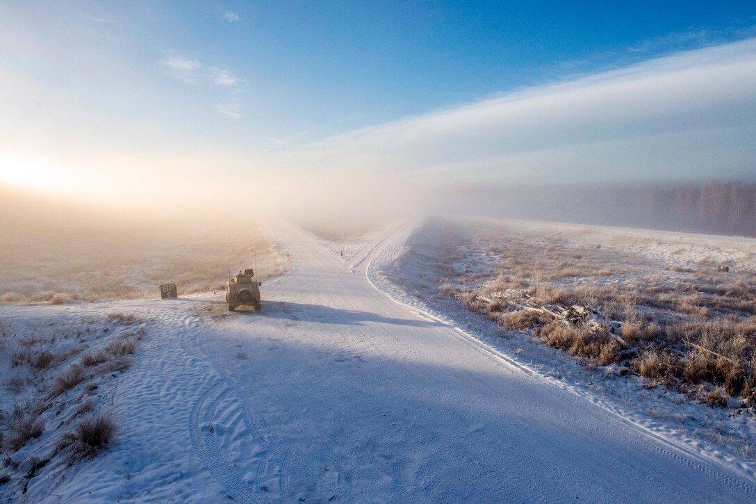 Soldiers in a vehicle wait for fog to lift on a snowy road.