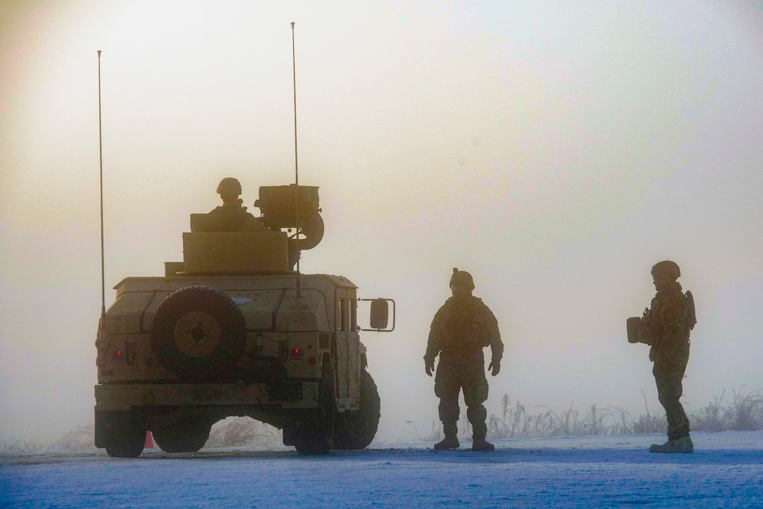 Three soldiers stand in the fog waiting for it to lift.