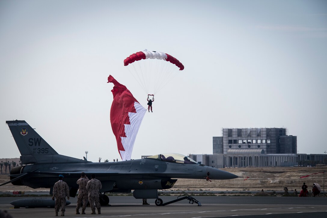 Bahrain Defense Forces parachute with the Bahrain flag above a U.S. Air Force F-16 Fighting Falcon at the Sakhir Air Base during the Bahrain International Airshow (BIAS) 2018, Bahrain, Nov. 14, 2018. BIAS is a biennial, three-day aviation and aerospace industry event that provides the U.S. military an opportunity to highlight DOD aviation’s flexibility, speed and agility. (U.S. Air Force photo by Senior Airman Gracie I. Lee)