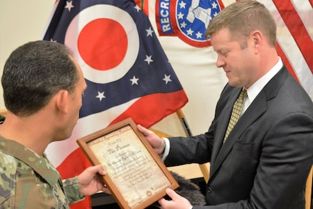 Soldier presenting Under Secretary with honorary certificate.