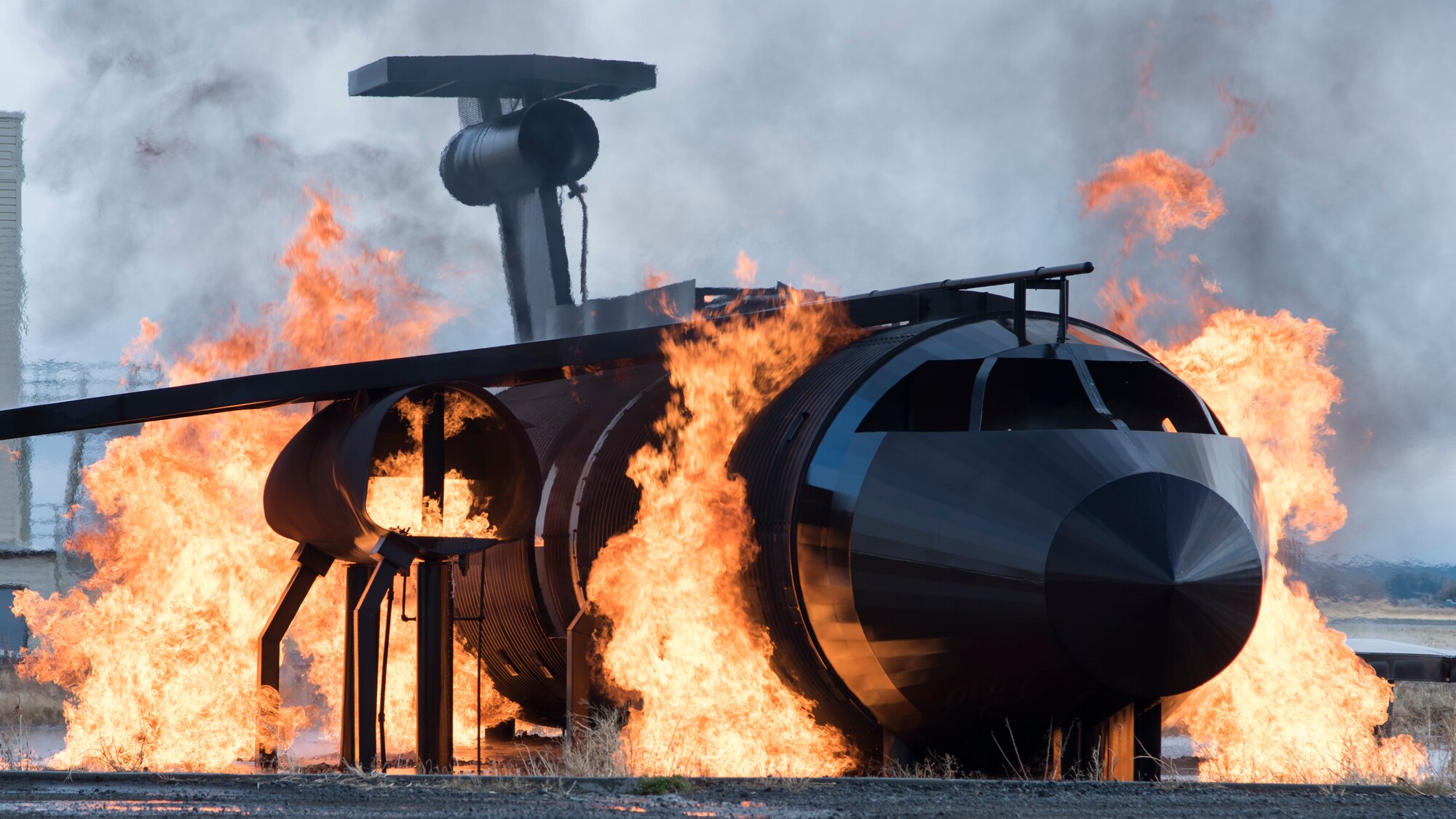 A dummy aircraft burns in the 92nd Civil Engineering Squadron Fire Department training area during a demonstration for members of the Spokane Local Emergency Planning Committee at Fairchild Air Force Base, Washington, Nov. 7, 2018. Team Fairchild firefighters use a dummy and simulate flames with safe propane gas to minimize environmental impact while maintaining readiness training efforts. (U.S. Air Force Photo/ Senior Airman Ryan Lackey)