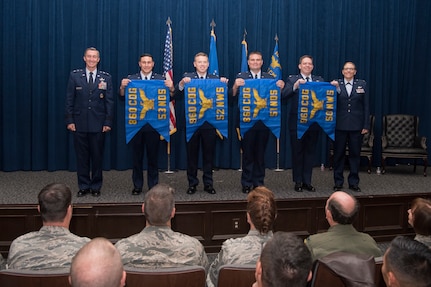 The commanders of four of the six newly activated subordinate units of the 960th Cyberspace Wing unfurled thier unit flags and posed for a photo with Maj. Gen. Ronald “Bruce” Miller, 10th Air Force commander, and Col. Lori Jones, the new 960th Cyberspace Wing commander.