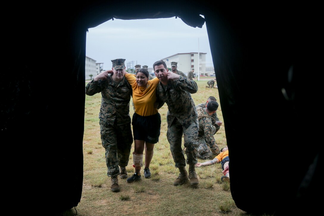 Sailors with 3rd Dental Battalion, 3rd Marine Logistics Group, bring in a notional casualty into a Role II facility for care during triage scenario training Nov. 16, 2018 at Camp Hansen, Okinawa, Japan. Sailors from dental clinics on Okinawa participated in Tactical Casualty Care to reinforce the basics of triage care for personnel involved in combat operations with support from Sailors with 3rd Medical Battalion. The various scenarios were chosen to depict common injuries that are seen during deployments. (U.S. Marine Corps photo by Lance Cpl. Armando Elizalde)