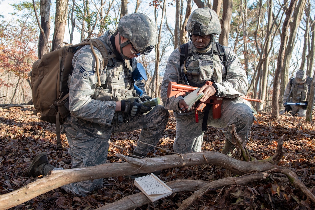 Senior Airman Mitchell Krause, 374th Security Forces Squadron patrolman, left, and Staff Sgt. Rayon McDonald 374 SFS flight chief, right, utilize a Defense Advanced GPS Receiver (DAGR) to mark coordinates in a notebook during a field training exercise at Camp Fuji, Japan, Nov. 8, 2018.