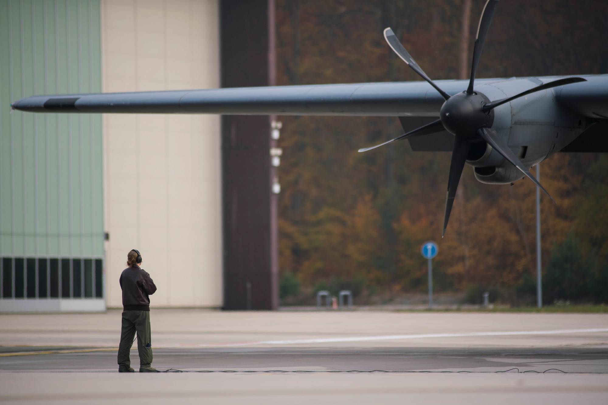 A 37th Airlift Squadron C-130J Super Hercules loadmaster stands ready before the aircraft’s engine is started on Ramstein Air Base, Germany, Nov. 6, 2018. Loadmasters stand by outside to verify there are no issues during engine startup. (U.S. Air Force photo by Senior Airman Devin M. Rumbaugh)