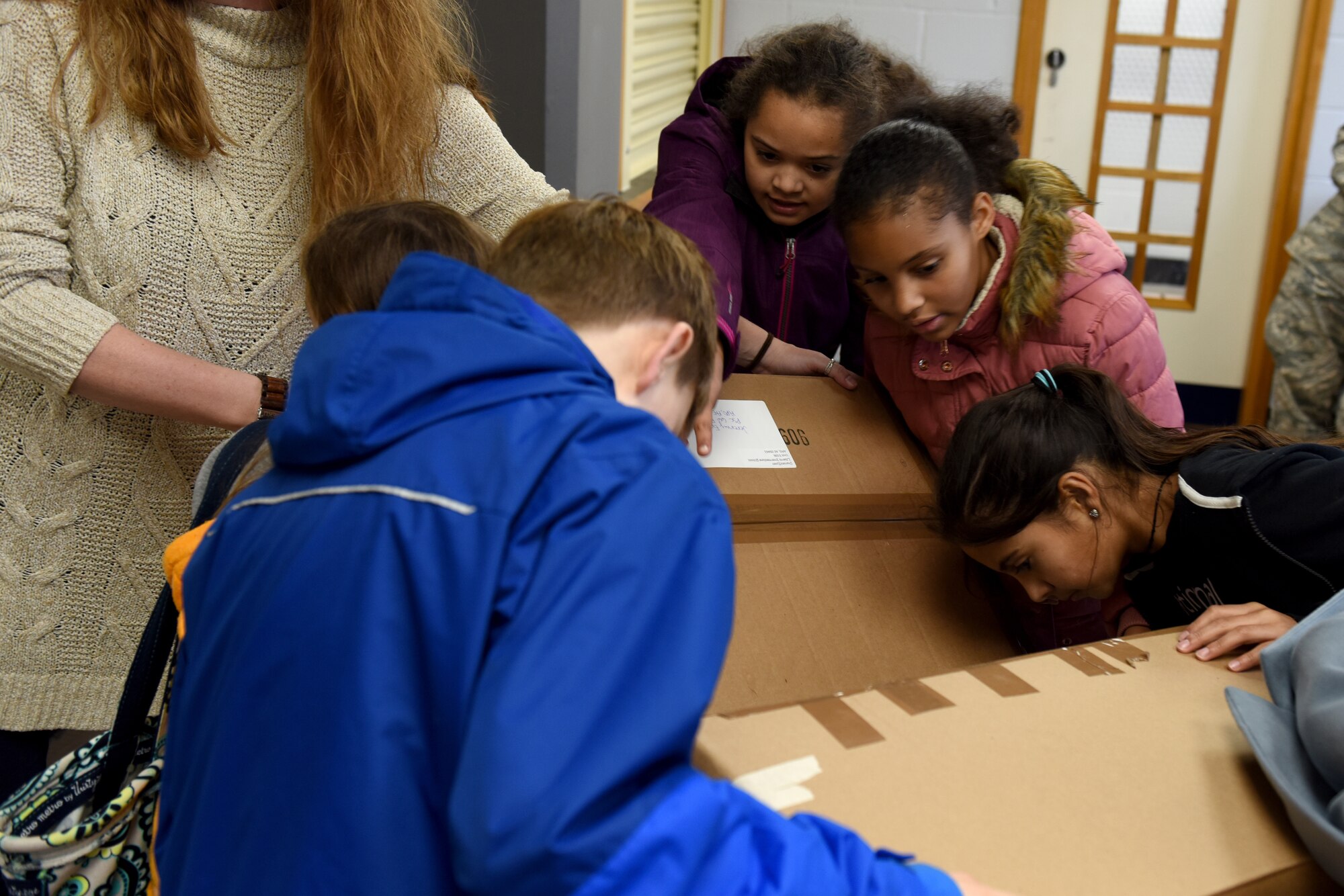 Students from Liberty Intermediate School inspect care package tracking numbers at Royal Air Force Lakenheath, England, Nov. 14, 2018. Students from the National Elementary Honors Society and Continuous School Improvement juniors created care packages with snacks, personal grooming items, entertainment and cards of support for deployed Liberty Wing firefighter and security forces members. (U.S. Air Force photo by Senior Airman John A. Crawford)