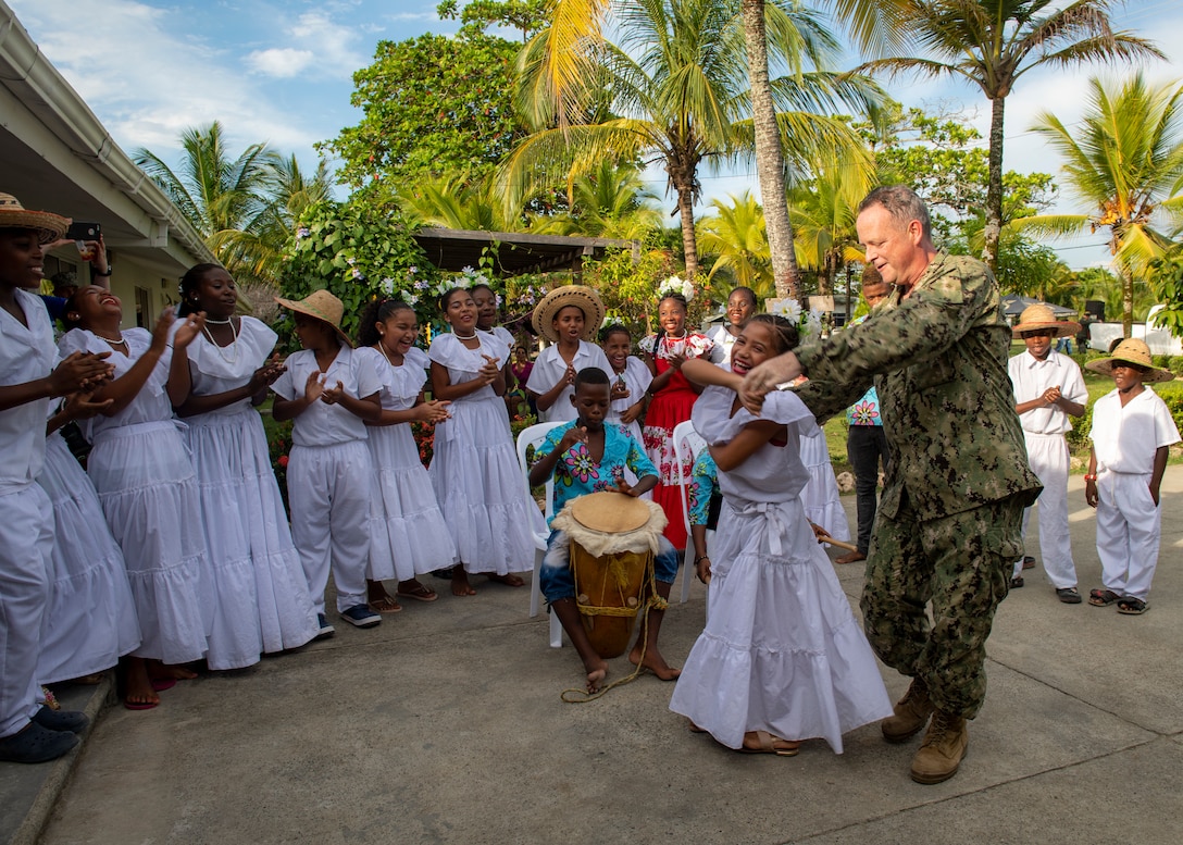 U.S. Navy Capt. Kevin Buckley, commanding officer, Medical Treatment Facility, of the hospital ship USNS Comfort (T-AH 20), dances with a member of a performance troupe following the opening ceremony at a land-based medical site.