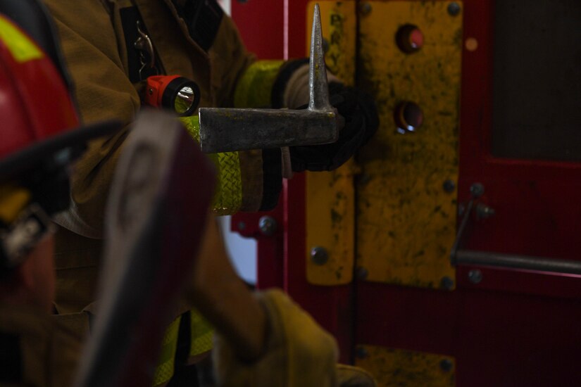 A Wide-ADZ Pro Bar is wedged into place by an axe during forced entry refresher training at the Newport News Fire Department in Newport News, Virginia, Nov. 16, 2018. There are many variables that determine what kind of tools a firefighter will use when forcibly entering a building, the kind of door, the type of locks and what tools they have available at the time. (U.S. Air Force photo by Senior Airman Derek Seifert)