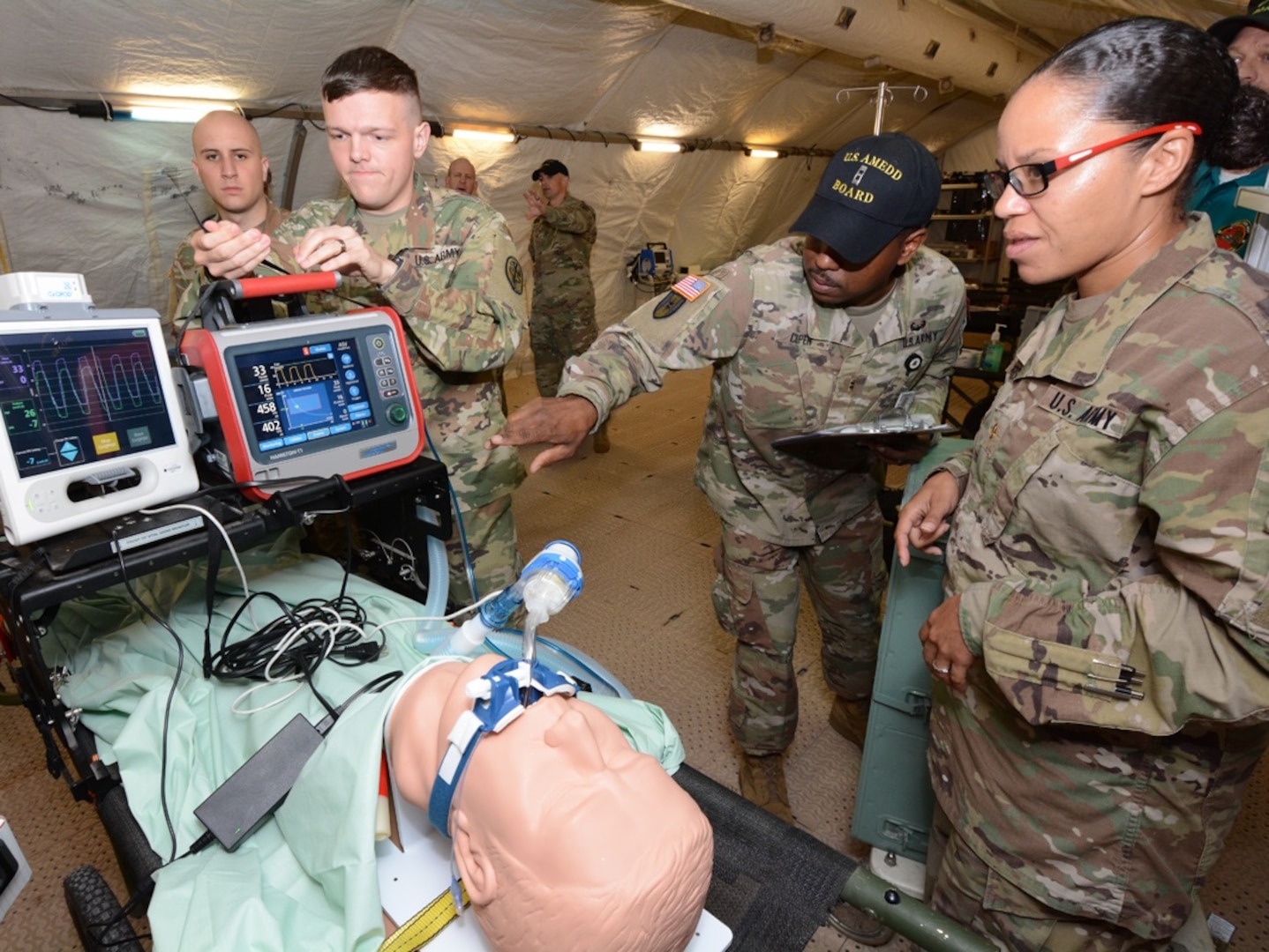 Chief Warrant Officer 2 Goldie Cooper (center), Army Medical Department Board, checks the status of the intrathoracic pressure regulation therapy, or IPRT device at a deployable medical systems equipment of training, or DMSET, complex at Joint Base San Antonio-Camp Bullis Nov. 7.