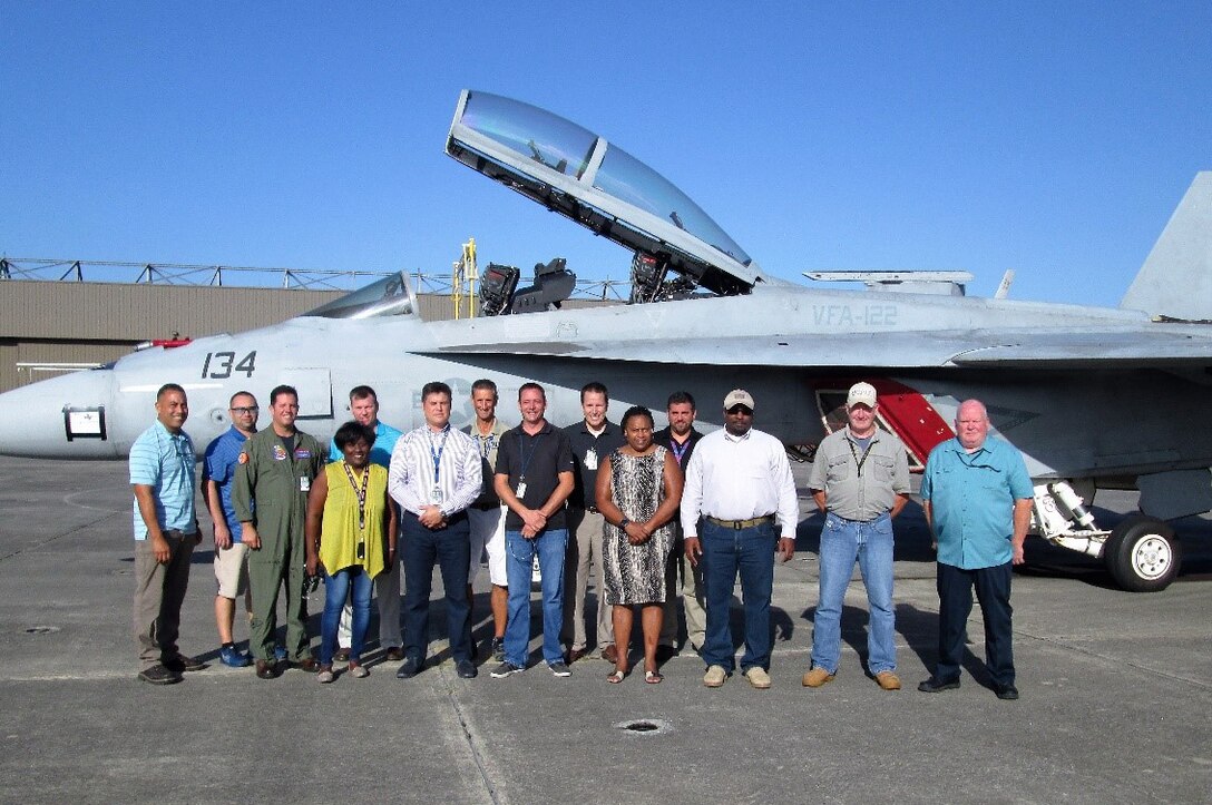 14 people pose in front of a fighter jet