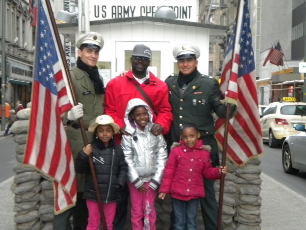 Family poses for photo with German Soldier re-enactors at Checkpoint Charlie.