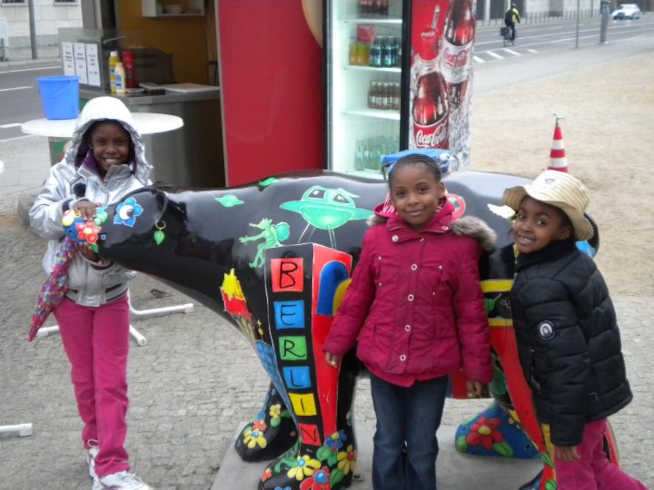 Three children pose for photo with local Berlin polar bear landmark.