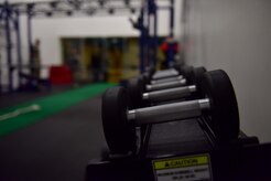 Dumbbells are in focus with workout equipment in the background.