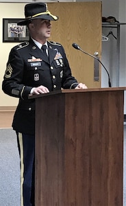 Soldier in dress uniform giving a speech in front a podium with a cavalry hat on