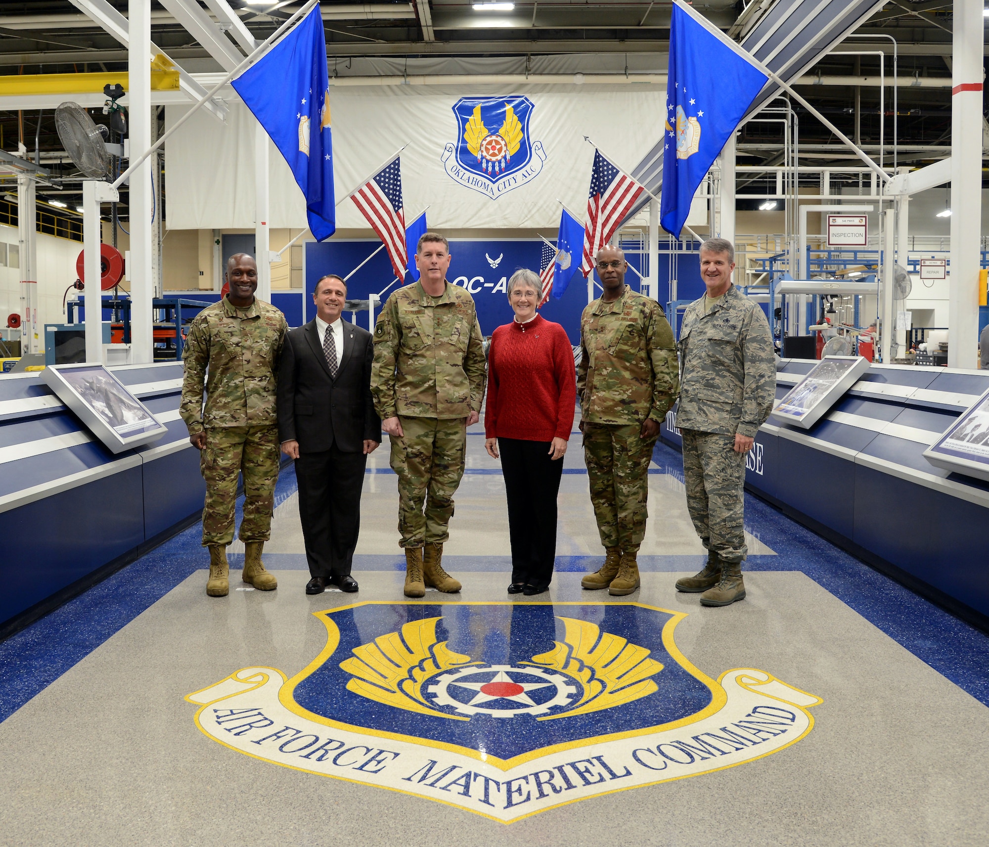 Col. Kenyon Bell, 72nd Air Base Wing commander; Kevin Stamey, Air Force Sustainment Center executive director; Lt. Gen. Gene Kirkland, AFSC commander; Secretary of the Air Force Heather Wilson; Maj. Gen. Cedric George, director of Logistics, deputy chief of staff for Logistics, Engineering and Force Protection and Brig. Gen. Christopher Hill, Oklahoma City Air Logistics Complex commander pose for a photo with the Air Force Materiel Command emblem located at Hollywood and Vine in Bldg. 3001. Wilson visited Tinker Nov. 16 and toured several facilities and organizations. She announced at the end of her tour that Tinker Air Force Base has been selected as the base that will support the maintenance and sustainment operations for the B-21 Raider, the next generation long-range bomber sometime in the mid-2020s.