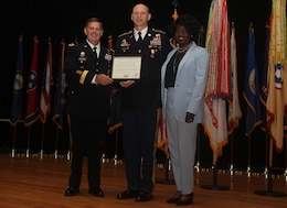 FORT KNOX, Ky. - Command Sgt. Maj. Jason Willett, senior enlisted advisor, 1st Theater Sustainment Command, (middle), Maj. Gen. Flem B. "Donnie" Walker, Jr., commanding general of 1st TSC, left, and Willetts wife, Vemetress Willett pose as Willett receives his Army retirement plaque, Oct. 23. Willett dedicated 26 years to service in the Army, caring for the Army's greatest assets - its Soldiers. (U.S. Army photos by Spc. Zoran Raduka)