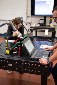 Anieka Bouchard and Seth Boemmels, both from Portsmouth Naval Shipyard, pair up to operate a portable coordinate measuring machine at a training session conducted by PSNS & IMF employees.