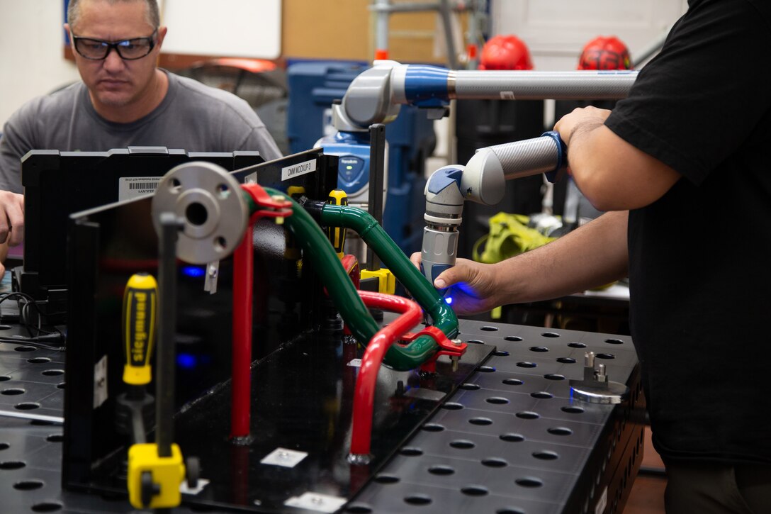 Gavin Mapa, Pearl Harbor Naval Shipyard, receives training on using a portable coordinate measuring machine at Puget Sound Naval Shipyard and Intermediate Maintenance Facility.