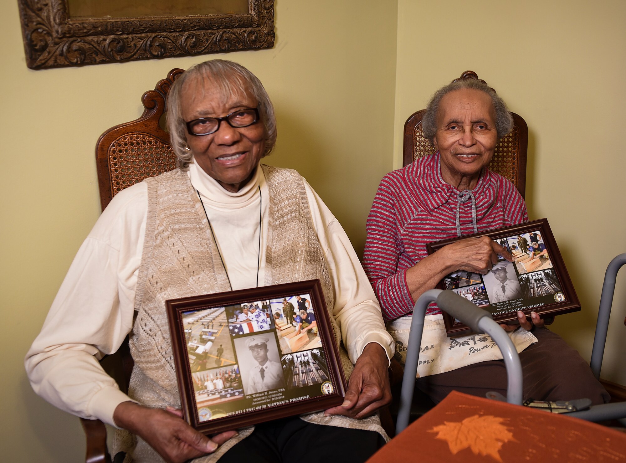Ida Jones-Dickens, left, and Elizabeth Jones-Ohree hold collages presented to them by the Defense POW/MIA Accounting Agency (DPAA) at Elizabeth’s home in Rocky Mount, North Carolina, Nov. 15, 2018.