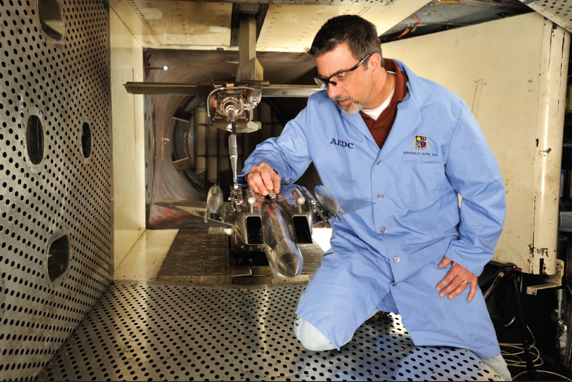 Engineer David Anderson inspect the 1/20-scale model of an F-15E Strike Eagle Aircraft and a sting-mounted Small Diameter Bomb during a break in the ongoing store separation test for the weapon’s development phase trials in the 4-foot transonic wind tunnel at Arnold Air Force Base. (U.S. Air Force photo by Rick Goodfriend)