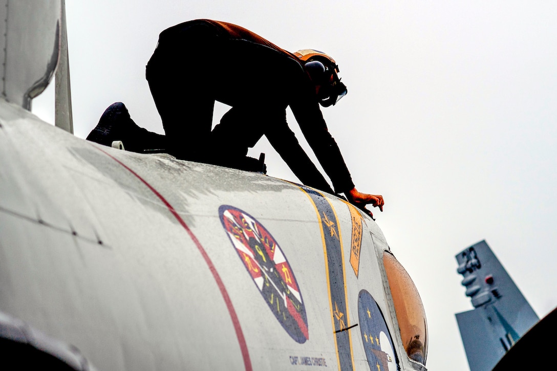 A sailor conducts maintenance on an E-2C Hawkeye aircraft.