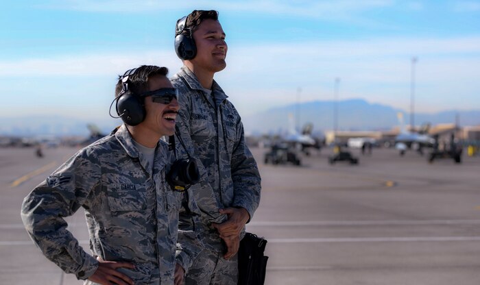 Airman 1st Class Bonifacio Garcia, 757th Aircraft Maintenance Squadron Strike Aircraft Maintenance Unit F-15E Strike Eagle fighter jet maintainer and Airman 1st Class Tom Sweeney, 757th Aircraft Maintenance Squadron Strike Aircraft Maintenance Unit F-15E Strike Eagle fighter jet weapons personnel, observe an F-15E take off Nov. 15, 2018 at Nellis Air Force Base, Nevada. Garcia and Sweeney were participants in the maintenance and munitions portion of the Gunsmoke Competition held at Nellis. (U.S. Air Force photo by Airman Bailee A. Darbasie)