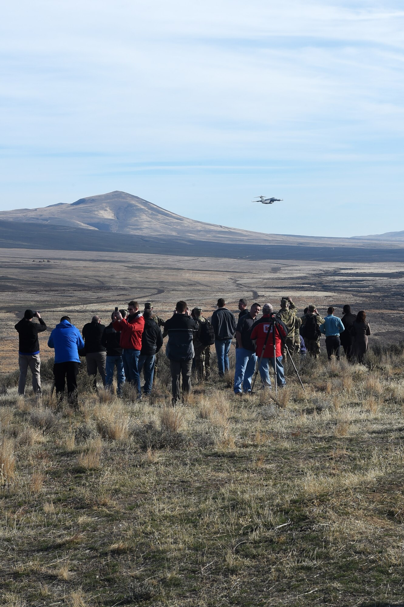 Spectators watch as a McChord C-17 Globemaster III flies away from the Selah Airstrip on Yakima Training Center, Washington, November 15, 2018.