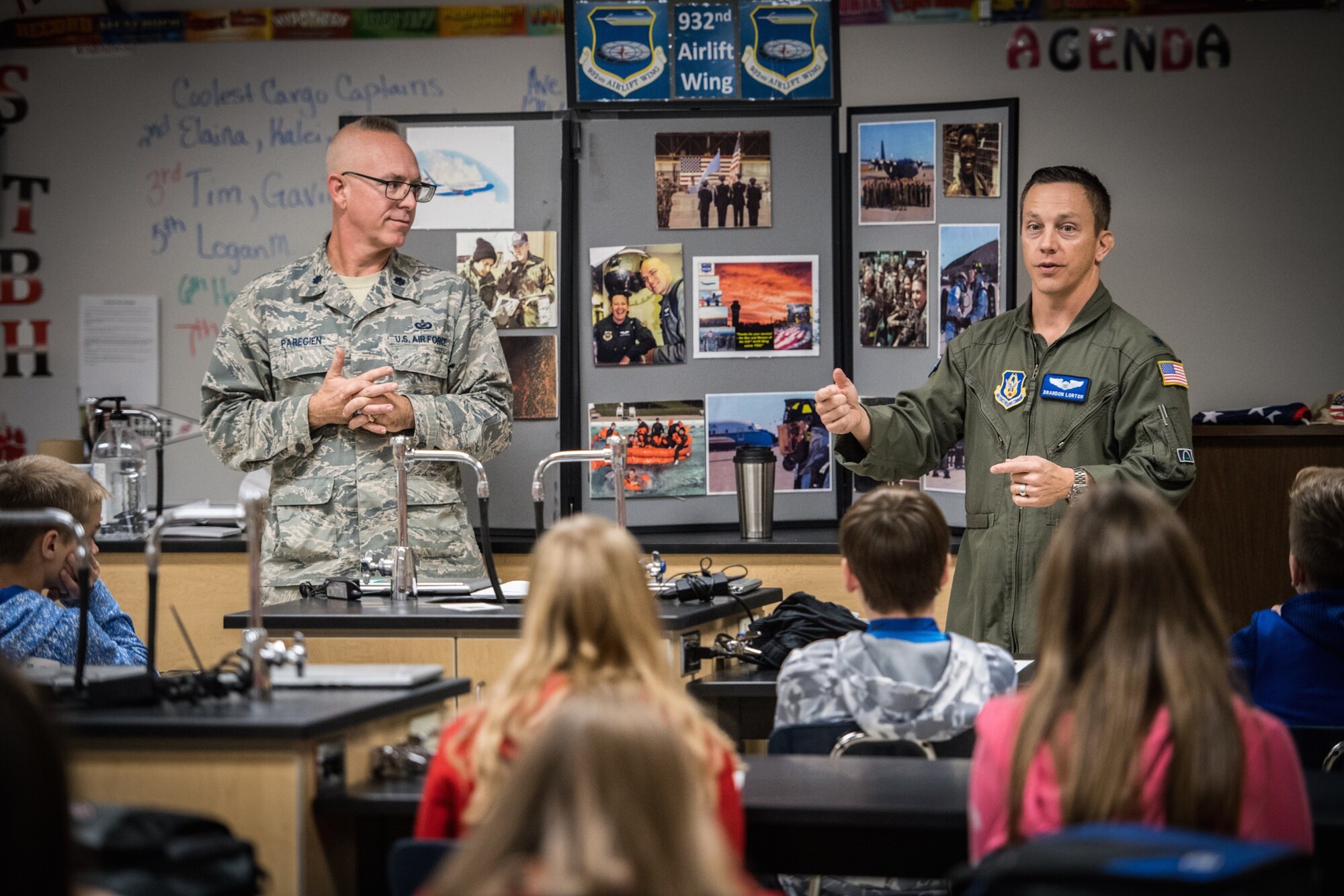 One of the 932nd Airlift Wing's 73rd Airlift Squadron pilots, Lt. Col. Brandon Lorton, speaks to the Highland Junior High regarding the mission of the 932nd Airlift Wing, patriotism, flying and remembering veterans. He joined the wing's public affairs officer, Lt. Col. Stan Paregien at left, to set up a 932nd AW display booth and answer a wide variety of questions about the Air Force Reserve.  They handed out some military gear for students to pass around, along with an American flag, and answered student's questions about what it takes to become an American Airman during an all Veterans Day event held Nov. 9, 2018.  (U.S. Air Force photo by Master Sgt. Chris Parr)