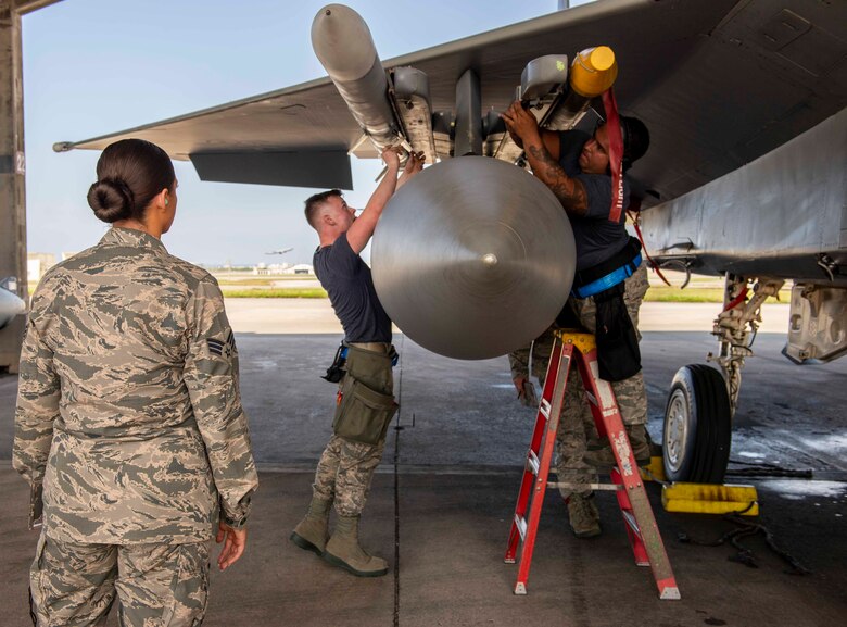 U.S. Air Force Airman 1st Class Brandon Carson, 44th Aircraft Maintenance Unit weapons load crew member, left, and Staff Sgt. Eric Llaguno, 44th AMU weapons load crew chief, work together to load munitions while being evaluated during a load competition Oct. 26, 2018, at Kadena Air Base, Japan. Later, the 44th AMU was announced the winner of the competition.