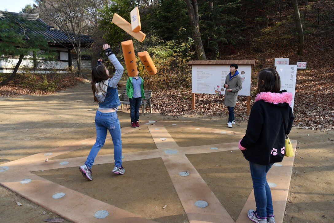 A local guide teaches children from U.S. Army Garrison Humphreys, Republic of Korea how to play yut, a traditional Korean board game, at the Korean Folk Village, Yongin, ROK, Nov. 13, 2018. In addition to visiting the Korean Folk Village, participants in the two-day Head Start Program attended classes about the history, culture and language of South Korea and received a hands-on demonstration of the public transportation system. (U.S. Air Force photo by Senior Airman Kelsey Tucker)