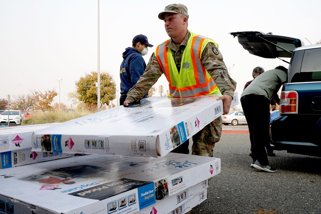 A service member unloads boxes from a vehicle.