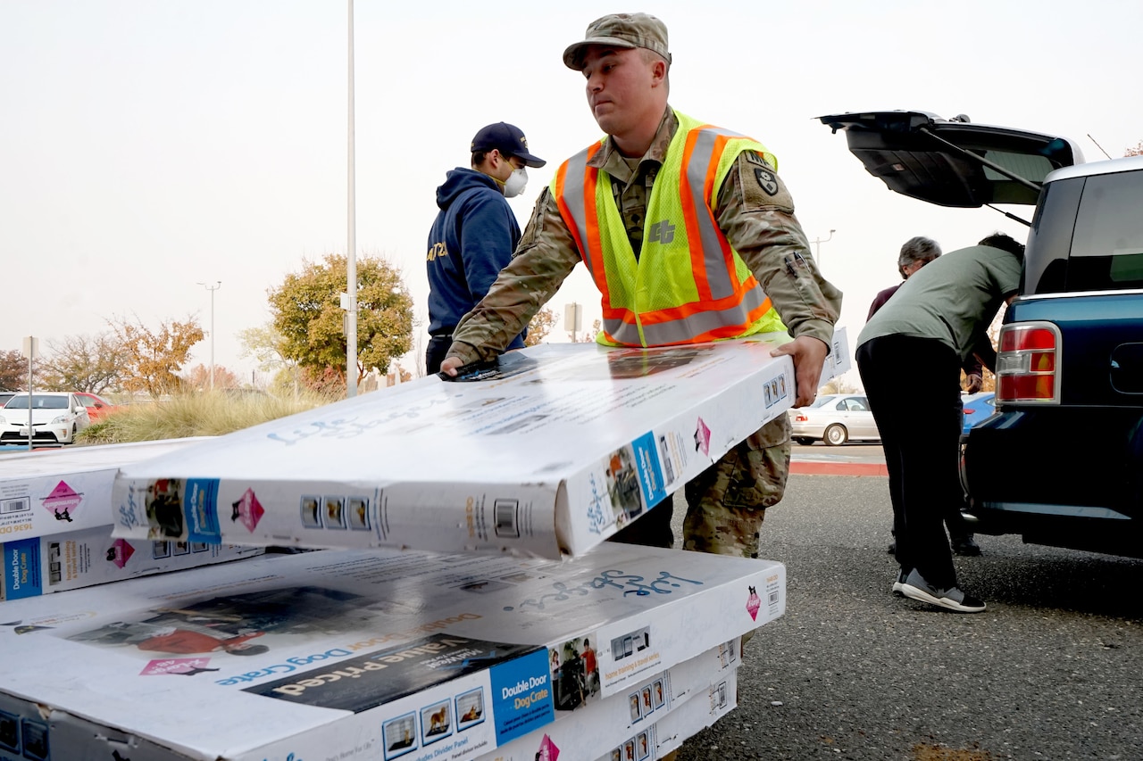 A service member unloads boxes from a vehicle.