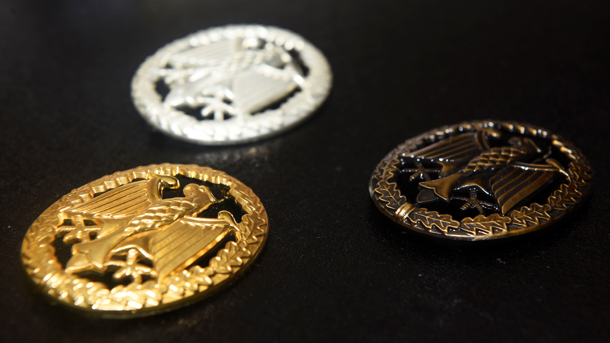 Three German Armed Proficiency Badges lie ready to be pinned onto candidates who successfully completed all events during the GAPFB competition Nov. 18, 2018, at Eastern Washington University in Cheney, Washington. The badge is divided into three different levels of proficiency and each is represented by a gold, silver or bronze medal. A point average system is used to calculate which medal each participant will receive. (U.S. Air Force photo/Airman 1st Class Lawrence Sena)