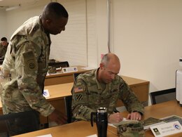 FORT KNOX, Ky. - Lt. Col. Barry Murray, deputy chief of the Strategic Operations and Plans (SOaP) for the 1st Theater Sustainment Command (TSC) Blue Team, assists Maj. John Krigbaum, network assurance officer-in-charge during an SOaP team academic quiz. Forty Soldiers spent a week in the classroom learning the mission of the SOaP team before deploying to Kuwait. (U.S. Army photo by Mr. Brent Thacker)