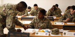 FORT KNOX, Ky. - Lt. Col. Barry Murray, deputy chief of the Strategic Operations and Plans (SOaP) for the 1st Theater Sustainment Command (TSC) Blue Team, assists Sgt. 1st Class Alaine Gilpin, plans non-commissioned officer during an SOaP team academic quiz. Forty Soldiers spent a week in the classroom learning the mission of the SOaP team before deploying to Kuwait. (U.S. Army photo by Mr. Brent Thacker)