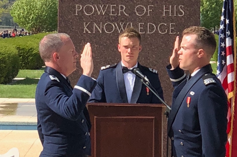 Two men raise hands in an Air Force commissioning ceremony