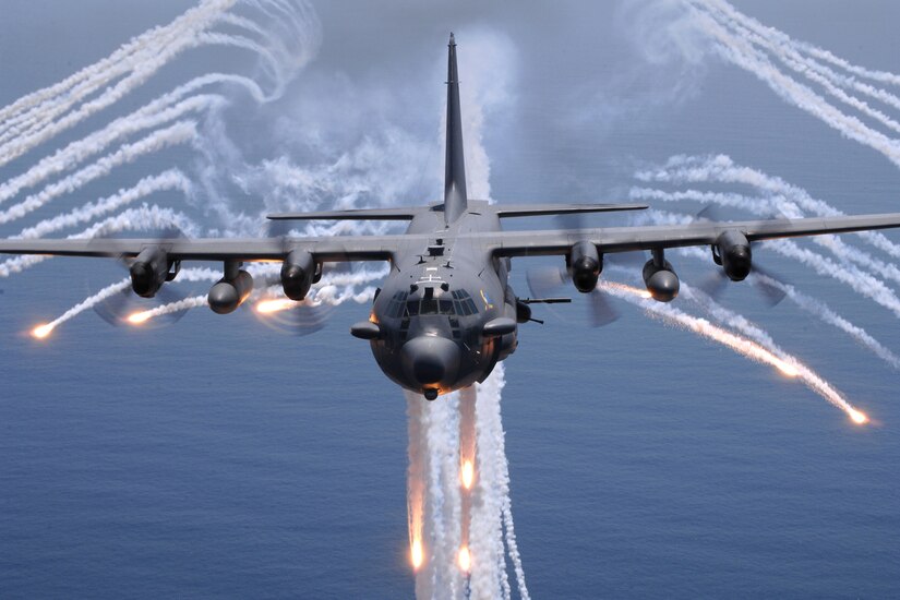 A military jet sends out flares in flight.