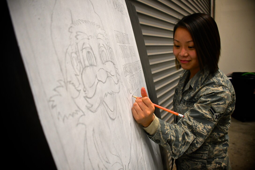 Airman 1st Class Kathryn Baskerville, 932nd Force Support Squadron, works during her lunch break, pencil designing a four foot by four foot wooden board display for a base wide holiday contest.  She and other workers in customer service area and all offices of the 932nd Airlift Wing will be out Thursday for the Thanksgiving federal holiday, but will return next week to continue painting the board at lunch after taking care of customers. The wing hopes all members and friends have a safe and restful day, and hope to see you again soon at the upcoming December 1-2, Unit Training Assembly weekend!  (U.S. Air Force photo by Lt. Col. Stan Paregien)