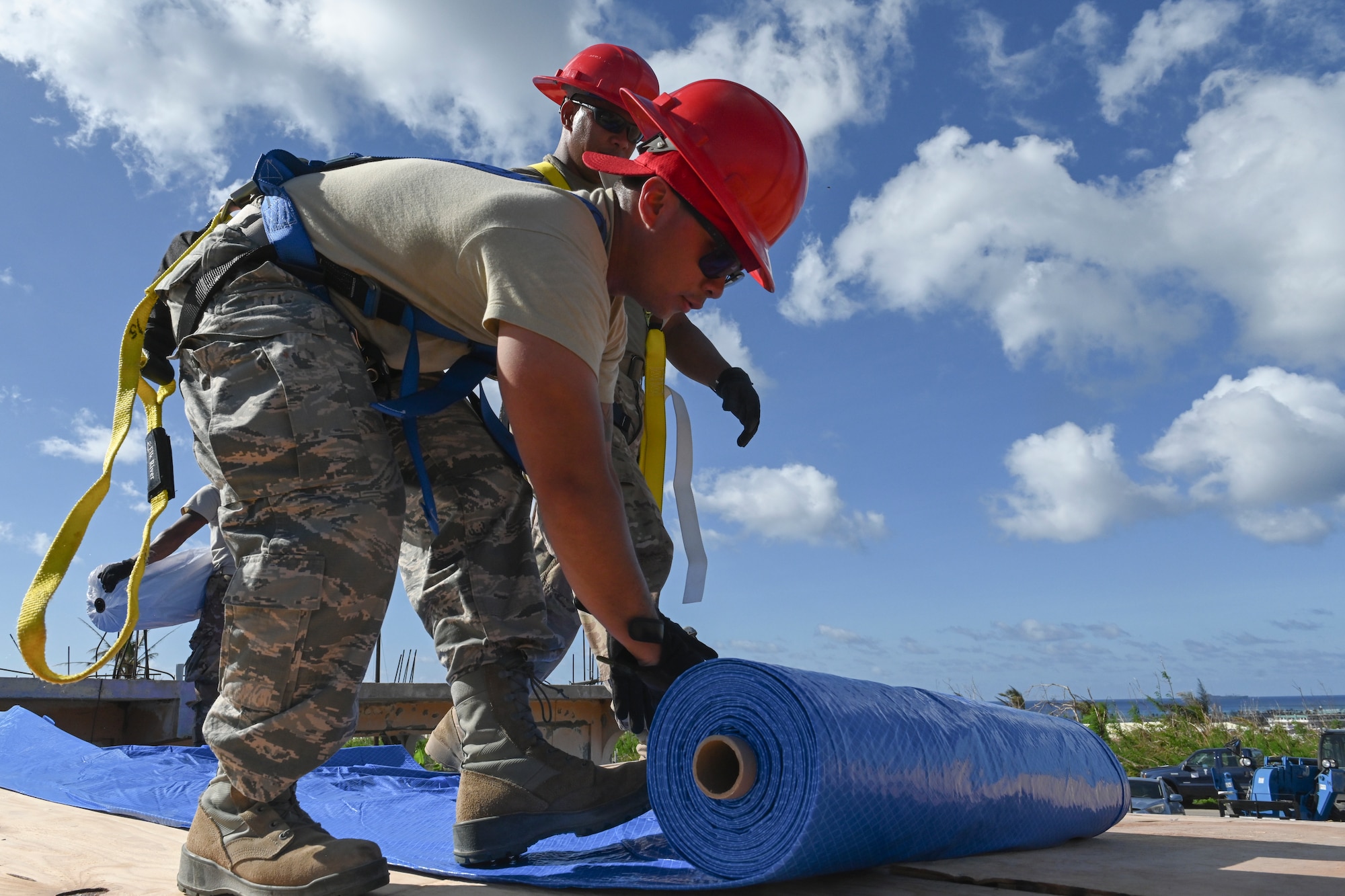 Senior Airman Jerome Solivar, 254th Rapid Engineer Deployable Heavy Operational Repair Squadron Engineers structural journeyman rolls out a tarp to help build a new roof for a home damaged by Super Typhoon Yutu, in the village of Koblerville, Saipan, Commonwealth of Northern Mariana Islands, Nov. 20, 2018.