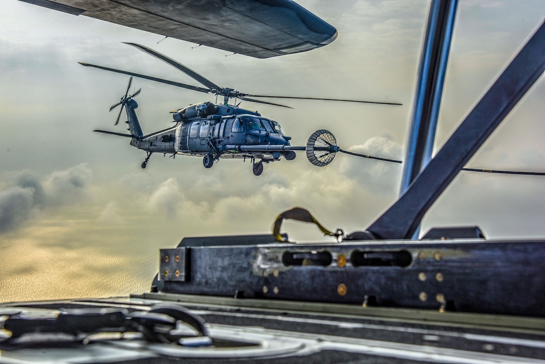 A helicopter receives fuel from an aircraft midair.