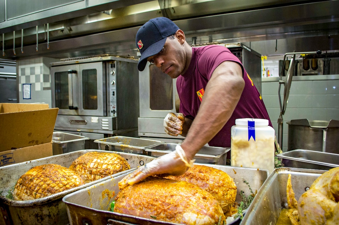 A soldier prepares several hams for a Thanksgiving feast.